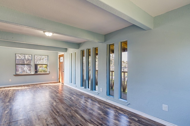 empty room with beam ceiling and dark hardwood / wood-style floors