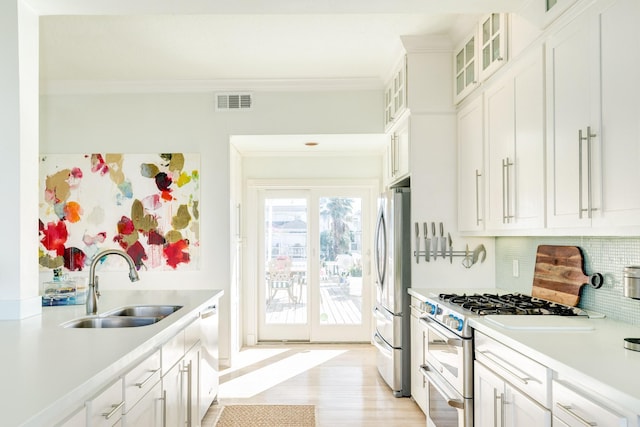 kitchen with sink, stainless steel appliances, white cabinets, backsplash, and crown molding