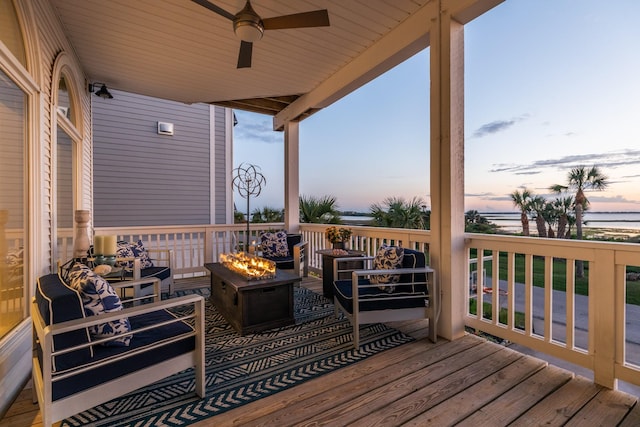 deck at dusk with ceiling fan and an outdoor living space with a fire pit