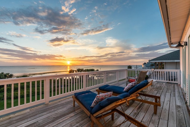 deck at dusk featuring a view of the beach and a water view