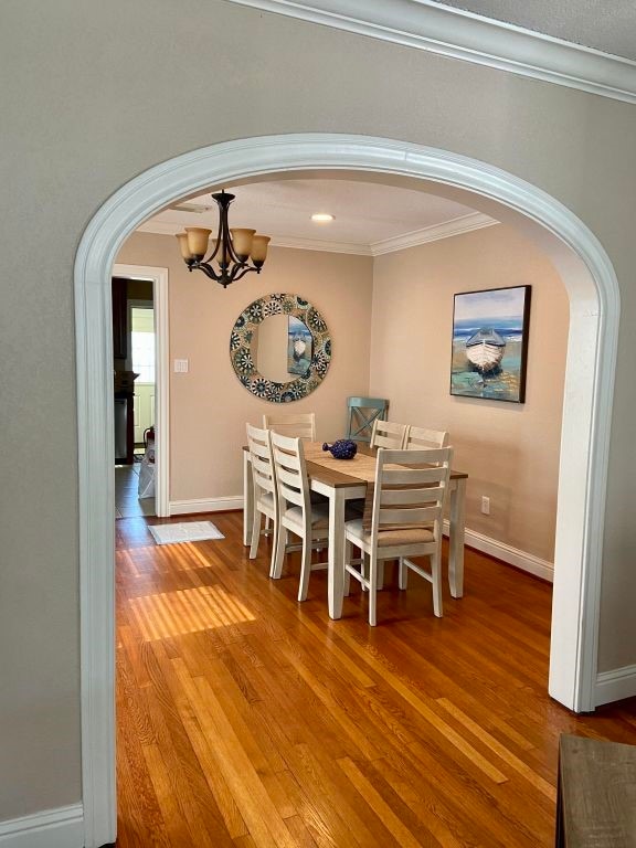 dining room featuring a chandelier, hardwood / wood-style flooring, and crown molding