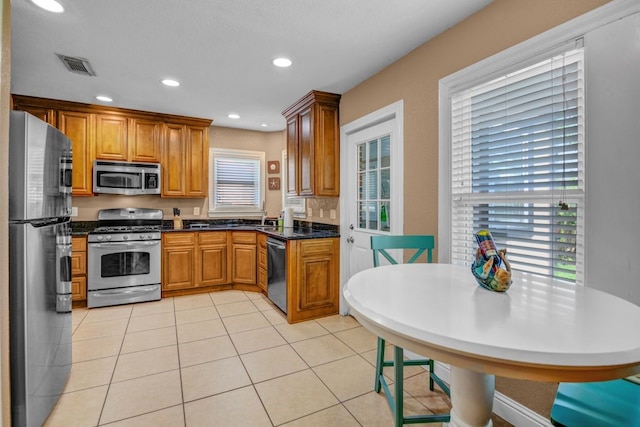 kitchen featuring dark stone counters, stainless steel appliances, sink, and light tile patterned floors