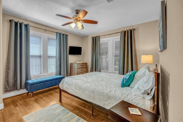 bedroom with hardwood / wood-style flooring, a textured ceiling, and ceiling fan