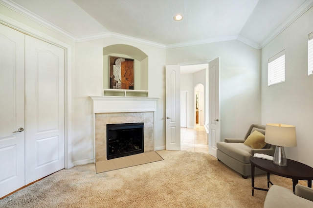 unfurnished room with lofted ceiling, a tile fireplace, ornamental molding, and light carpet