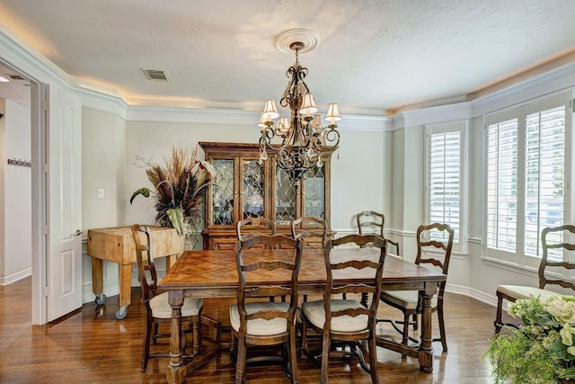 dining area featuring dark wood-type flooring, a notable chandelier, and crown molding