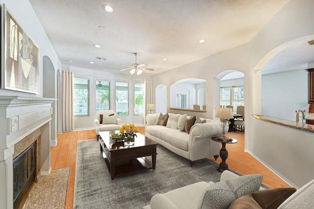 living room featuring sink, dark hardwood / wood-style flooring, a premium fireplace, and ceiling fan