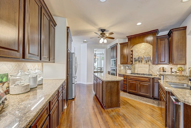 kitchen with light stone counters, appliances with stainless steel finishes, light hardwood / wood-style flooring, and sink