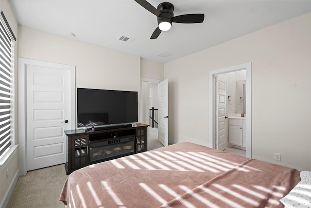 carpeted bedroom with ceiling fan, ensuite bathroom, and multiple windows