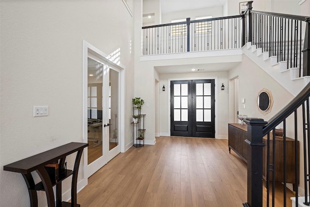 entrance foyer featuring a high ceiling, light hardwood / wood-style floors, and french doors