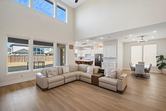 living room with a high ceiling, light hardwood / wood-style floors, and plenty of natural light