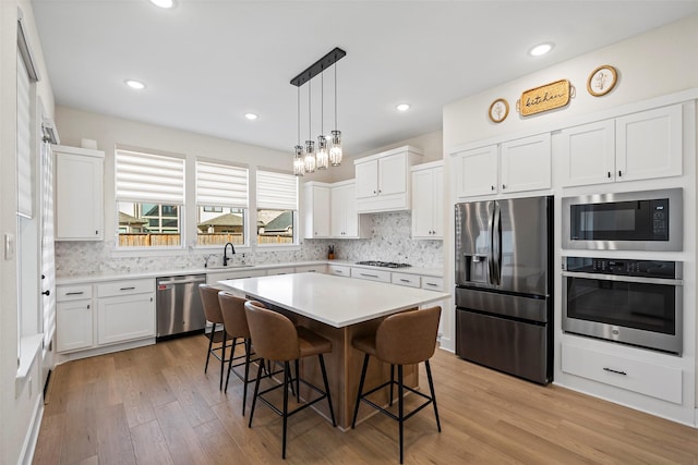 kitchen featuring a center island, a kitchen bar, sink, white cabinetry, and stainless steel appliances