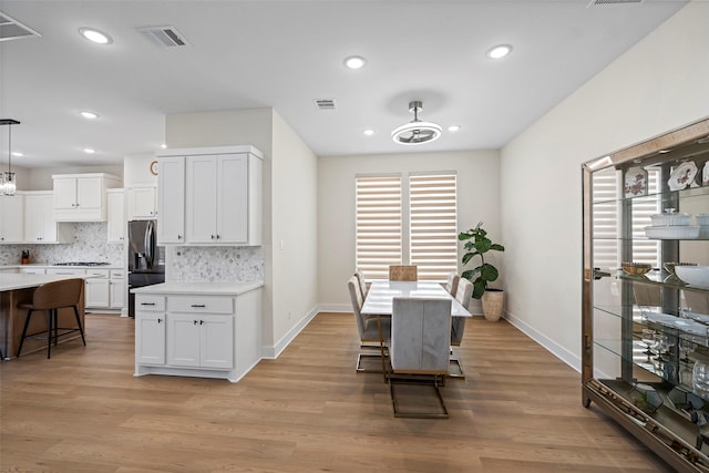 kitchen with hanging light fixtures, white cabinets, stainless steel fridge with ice dispenser, and a breakfast bar area