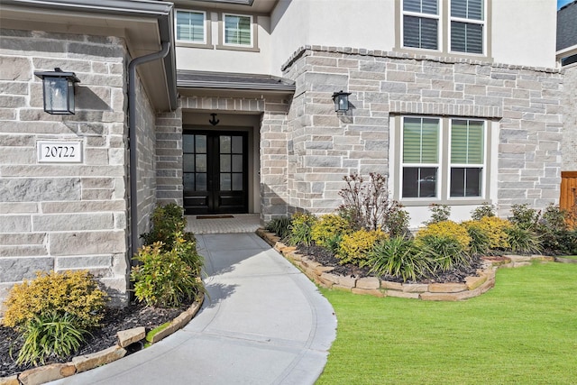 view of exterior entry featuring french doors and a yard