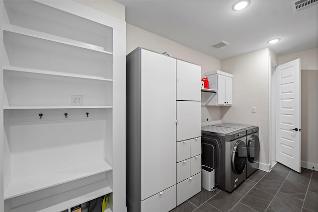 laundry area with washer and dryer, cabinets, and dark tile patterned floors