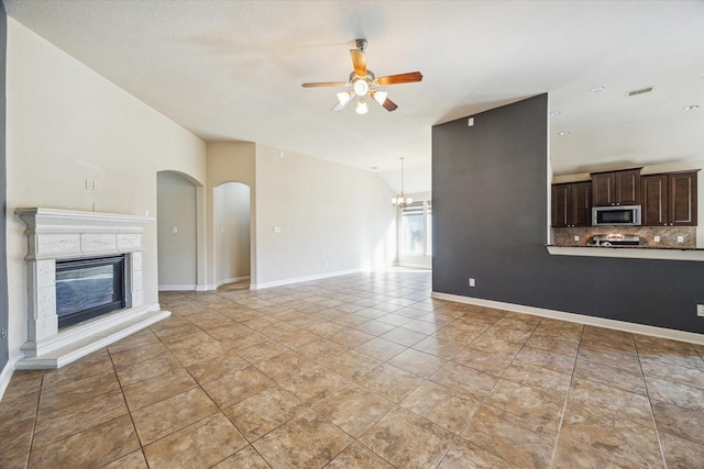 unfurnished living room with lofted ceiling, ceiling fan with notable chandelier, and light tile patterned floors