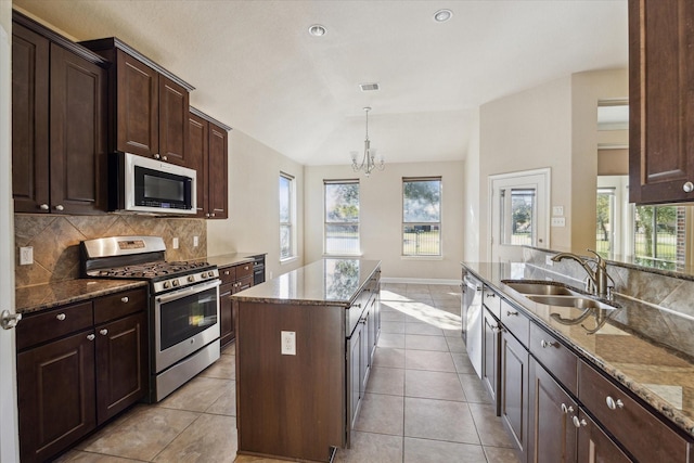 kitchen with a chandelier, appliances with stainless steel finishes, pendant lighting, a kitchen island, and sink