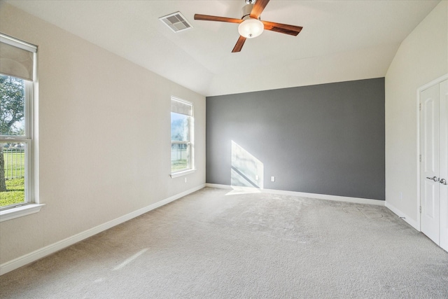 empty room featuring ceiling fan, carpet, a wealth of natural light, and vaulted ceiling