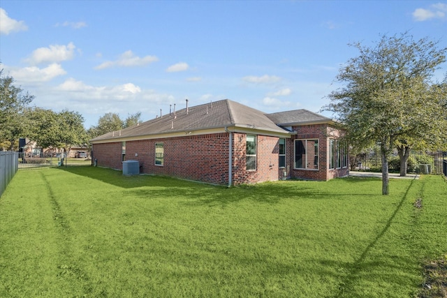 rear view of property with a yard and central air condition unit