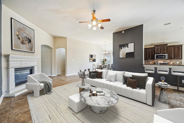 living room with ceiling fan with notable chandelier and vaulted ceiling