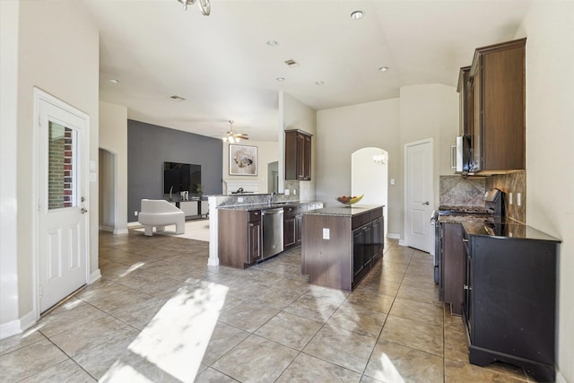 kitchen with ceiling fan, backsplash, dark brown cabinetry, a kitchen island, and appliances with stainless steel finishes