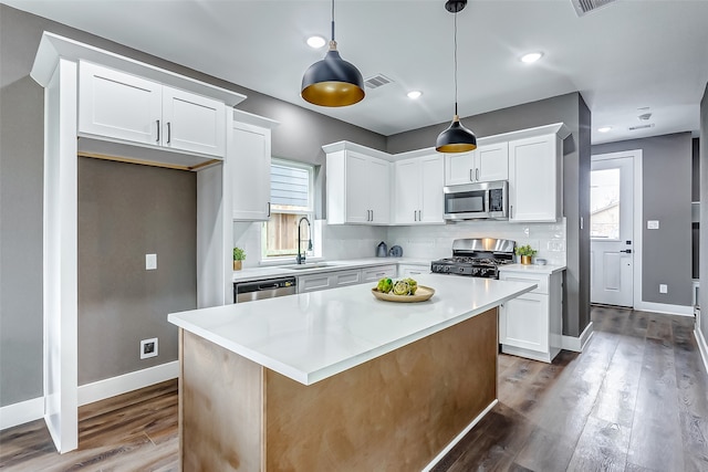 kitchen featuring appliances with stainless steel finishes, pendant lighting, sink, white cabinets, and a center island