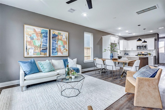 living room featuring dark wood-type flooring and ceiling fan