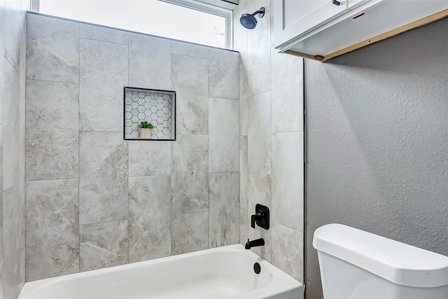 bathroom with tiled shower / bath combo and toilet