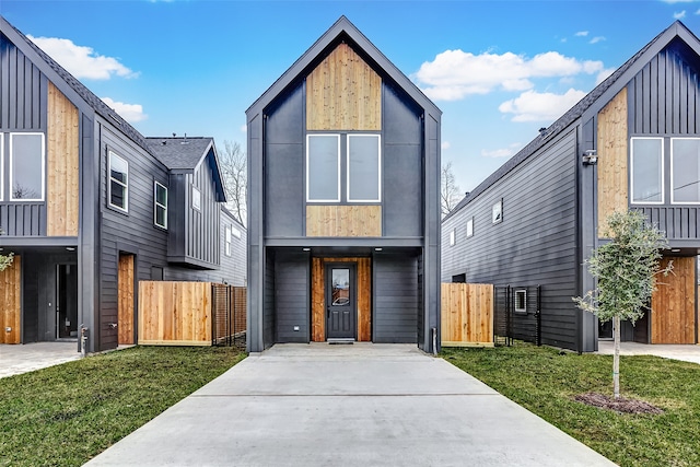 contemporary home with a gate, a front yard, and fence