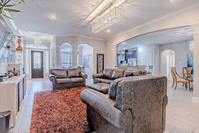 living room with a notable chandelier, ornamental molding, and ornate columns