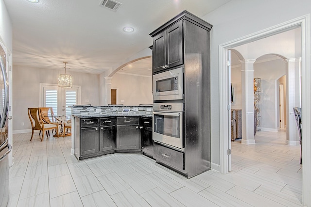 kitchen featuring stainless steel appliances, an inviting chandelier, ornate columns, backsplash, and hanging light fixtures