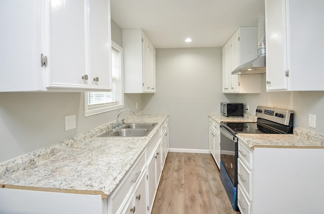 kitchen featuring light hardwood / wood-style floors, stainless steel appliances, white cabinets, wall chimney range hood, and sink