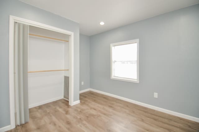 unfurnished bedroom featuring light hardwood / wood-style floors and a closet