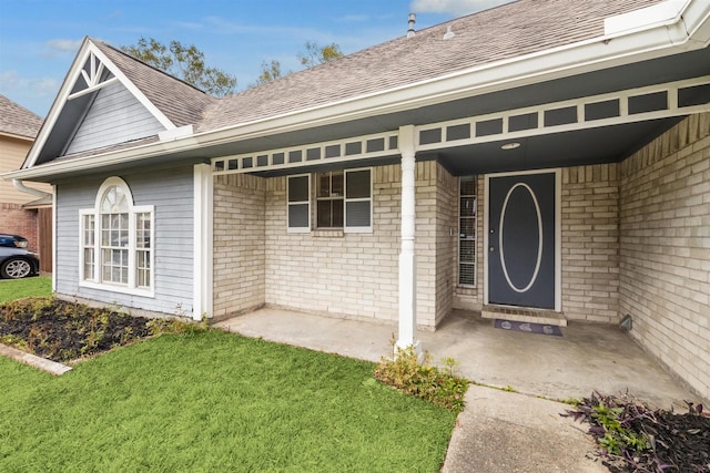 view of exterior entry featuring a lawn