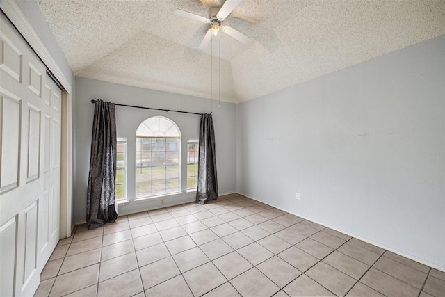 spare room featuring light tile patterned flooring, a textured ceiling, and vaulted ceiling