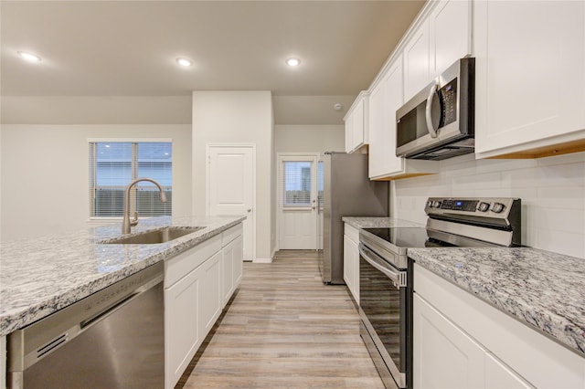 kitchen featuring stainless steel appliances, sink, white cabinetry, light hardwood / wood-style flooring, and light stone countertops