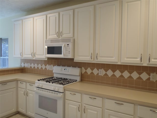 kitchen featuring white appliances, white cabinets, and tasteful backsplash