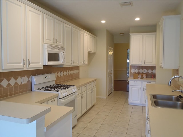 kitchen featuring white appliances, light tile patterned floors, tasteful backsplash, white cabinetry, and sink