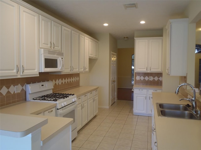 kitchen featuring white appliances, tasteful backsplash, white cabinetry, light tile patterned flooring, and sink