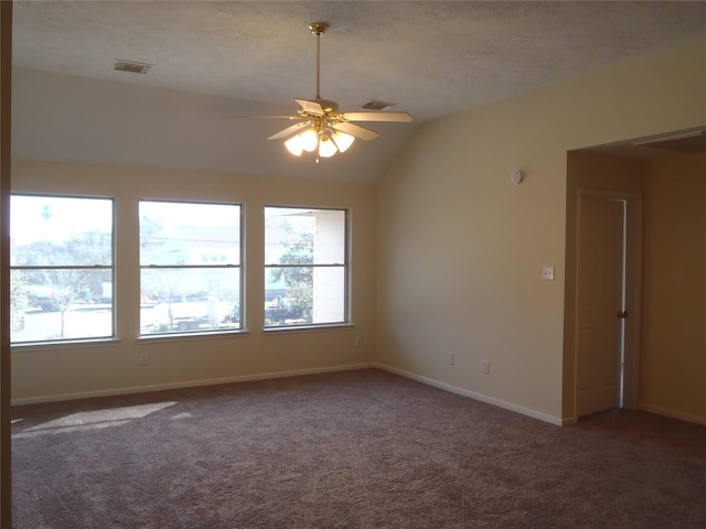 carpeted empty room featuring ceiling fan, vaulted ceiling, and plenty of natural light