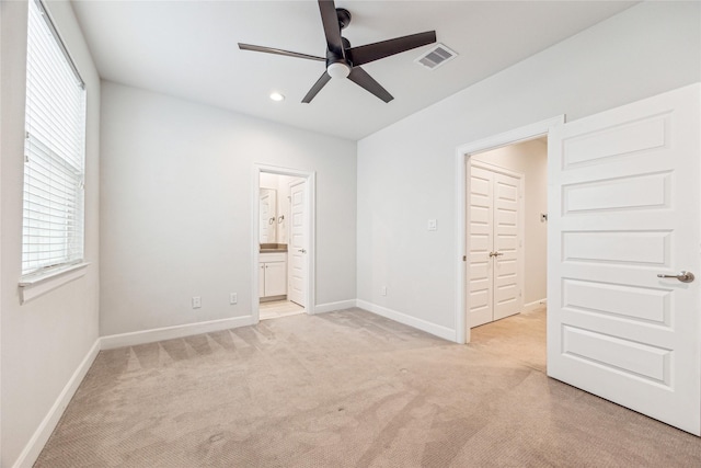 unfurnished bedroom with ensuite bathroom, a closet, ceiling fan, and light colored carpet