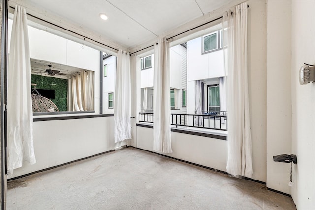 unfurnished sunroom featuring ceiling fan and plenty of natural light