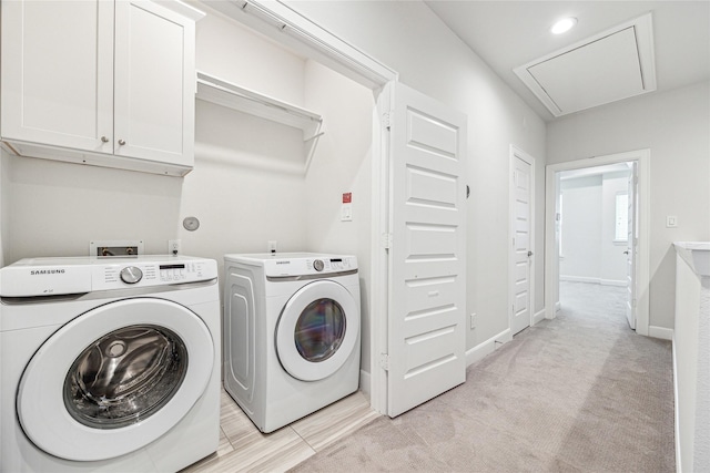 clothes washing area featuring washing machine and dryer, cabinets, and light carpet