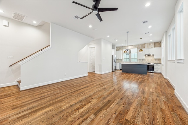 unfurnished living room featuring ceiling fan and dark wood-type flooring