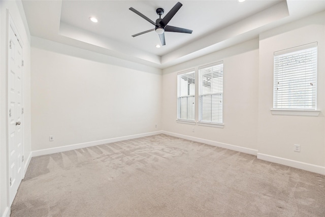 carpeted empty room featuring a raised ceiling and ceiling fan