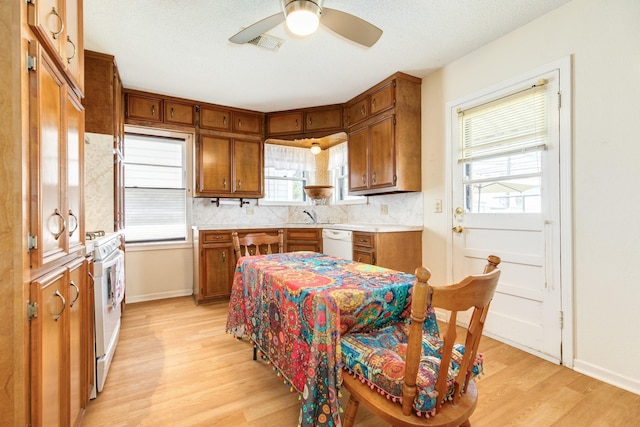 kitchen with light wood-type flooring, brown cabinets, visible vents, and light countertops