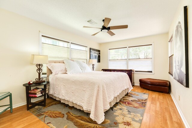 bedroom with visible vents, baseboards, light wood-style floors, and a ceiling fan