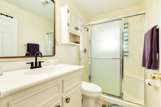 bathroom featuring visible vents, a shower stall, toilet, and vanity