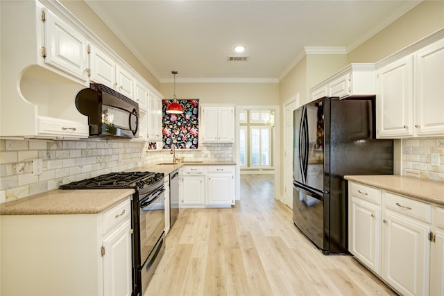 kitchen with white cabinets, ornamental molding, light hardwood / wood-style flooring, hanging light fixtures, and black appliances