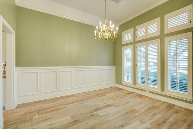 empty room with ornamental molding, light hardwood / wood-style floors, and an inviting chandelier