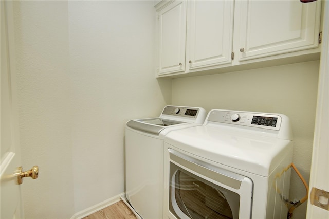 laundry room featuring light hardwood / wood-style flooring, cabinets, and washing machine and dryer